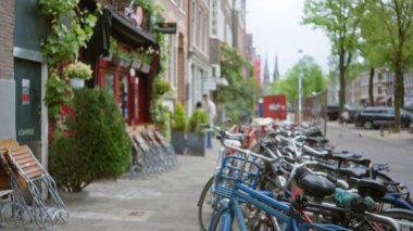 Bulanık bisikletler, Hollanda 'daki kentsel yaşamın özünü yakalayan canlı dükkanları ve yeşillikleriyle büyüleyici bir Amsterdam caddesi..
