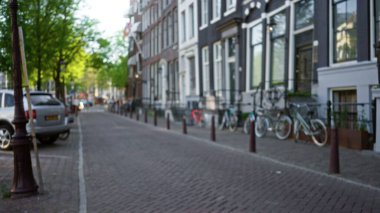 Odaklanmış bisiklet, araba ve tarihi mimarinin yer aldığı, sakin bir kentsel çevrenin özünü yansıtan Amsterdam Caddesi 'nin bulanık görüntüsü.