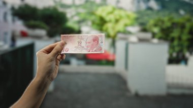 Kentin dışında bir sokakta elinde Türk lirası banknot tutan bir adam para önplanı sergiliyor.