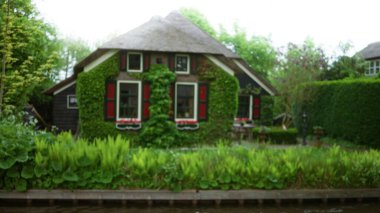 Sarmaşık kaplı duvarları ile büyüleyici giethoorn evi, sakin kanal sularına yansıyan, yemyeşil yemyeşil, Hollanda kırsalının huzurlu güzelliğini somutlaştıran.