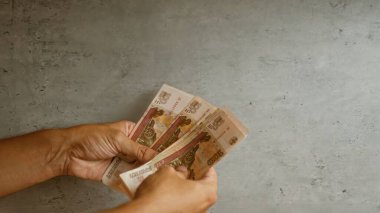 Adamın elleri somut bir zemine karşı Rus rublesi tutuyor. Bu da para ve beton yüzey detaylarını gösteriyor..