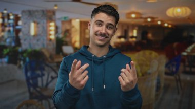 Otelde genç bir adam buraya gelip, modern dekorla karakterize edilmiş, mavi kapüşonlu bir jest yapıyor..