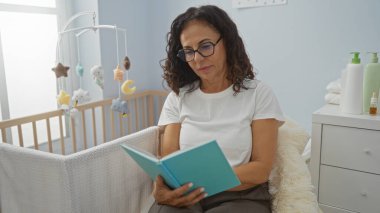 Yatak odasında, yumuşak ışık ve pastel dekorlu, huzurlu ve samimi bir atmosfer yaratan, beşikten beşiğe kitap okuyan bir kadın..