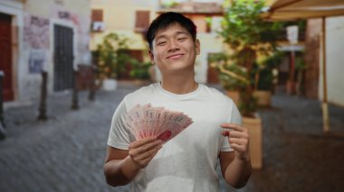 Elinde Tayvan banknotları olan genç bir adam bir gülümseme ile bir şehir merkezinde zenginlik sergiliyor neşeli bir ifadeyle..