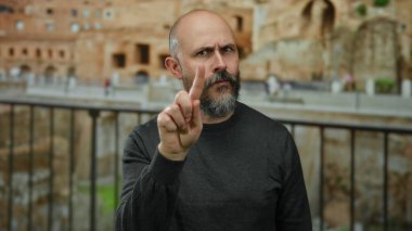 Roma 'da sakallı yakışıklı kel bir adam odaklanma ve niyetle jestler yapıyor, modern stille antik tarihi açık havada harmanlıyor..