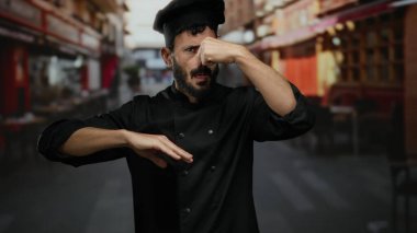 Sokakta aşçı, siyah üniforma giymiş, kötü kokuya karşı burun çimdikliyor, hoş olmayan kokulara karşı tepkisini vurguluyor..