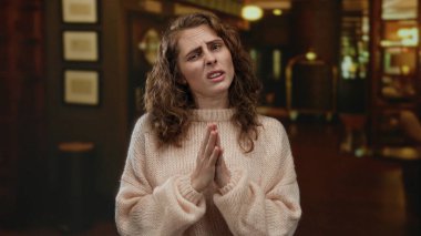 Sıcak bir otel ortamında sıcak ışıklandırmalı süveter giyen, ev ortamını vurgulayan bir kadın..