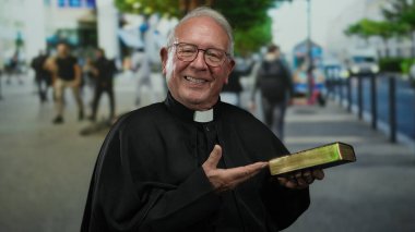 Başrahip elinde İncil 'le kalabalık bir caddede arka planda yürüyen yayalara gülümserken sakin bir şehir manzarasını resmediyor..