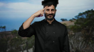 Siyah üniformalı İspanyol şef, doğadaki manzaralı dağ manzarasına karşı düşünceli bir davranış sergiliyor..