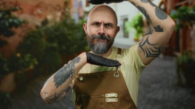 Tulum ve eldiven takmış sakallı kel bir adam tuhaf bir şehir caddesinde yaratıcı bir şekilde poz veriyor..