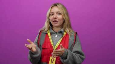 Sarı saçlı, canlı pembe bir arka plana karşı duygularını ifade eden, kırmızı yelek ve sarı ipli bir kadın gönüllü..