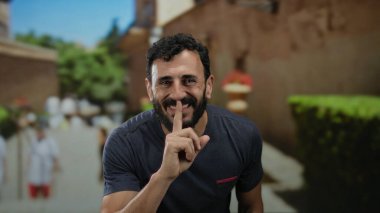 Sakallı İspanyol bir adam gülümsüyor ve güneşli bir sokakta sessizliğini koruyor. Arka planı bulanık. Huzuru ve huzurlu atmosferi vurguluyor.