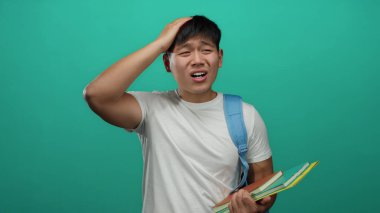 Beyaz tişörtlü ve mavi çantalı genç adam, yeşil bir geçmişe karşı hüzünlü bir ifadeye sahip defterler tutuyor. Öğrenci stresi ve hüsranına yol açıyor..