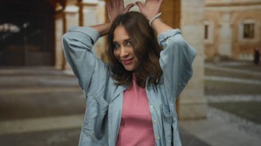 Eski bir üniversite binasında neşeli jestler yapan bir kadın gençlik ruhunu ve İspanyol mirasını tarihsel bir zemine karşı sergiliyor..