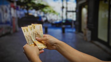 Kentsel bir caddede Norveç banknotları tutan adam, yoğun bir şehir ortamında iş yatırımını, döviz kurunu ve mali işlemleri sembolize ediyor.