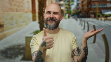 Dövmeleri olan kel bir adam şehir sokaklarında kendine güvenen, dövmelerini gösteren ve sıradan bir ortamda gülümseyen bir adam..