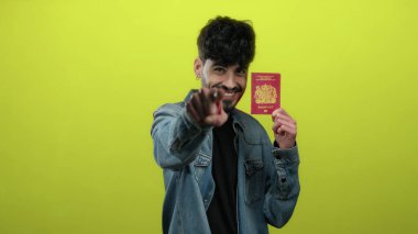 Elinde İngiliz pasaportu olan gülümseyen bir adam canlı sarı arka plana karşı izole edilmiş. Kimlik ve seyahat için hazır..