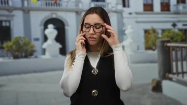 Şehir dışında telefonla konuşan bir kadın genç sarışın gözlüklü sohbet ayarlıyor..