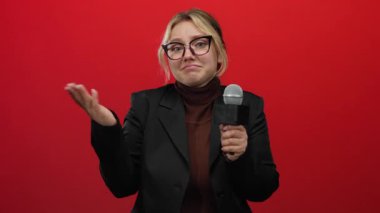 Kırmızı duvar arka planına karşı şaşkın ifadeli mikrofon tutan kadın muhabir izole edildi