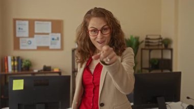 Modern ofis ortamında bilgisayar ve çizelgelerle çevrili kırmızı gömlek ve gözlük takan, motivasyon ve iş yerinde başarı taşıyan kadınlar..