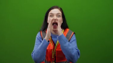 Ateşli yeşil arka plana karşı gönüllü yelek giyen esmer kadın, hareketli aksiyon sahnesinde heyecan ve enerji taşıyor..