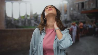 Roma harabelerinde boyun ağrısı çeken bir kadın, şehir ortamında antik bir alanı keşfederken rahatsızlık gösteriyor..