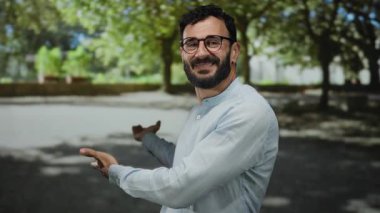 Sakallı İspanyol bir adam yeşil bir parkta ağaçların arasından süzülen güneş ışığıyla doğal bir ortam yaratıyor..