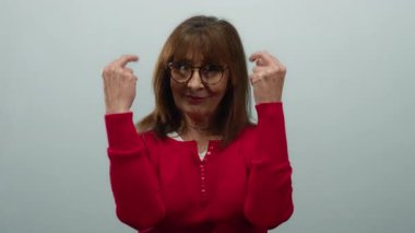 Kırmızı tişörtlü İspanyol son sınıf öğrencisi kadın beyaz arka planda orta parmaklı ve neşeli bir ifade sergiliyor..