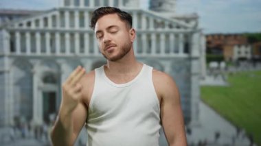 Sakallı genç adam güneşli bir günde arka planda tarihi bir binayla şehir caddesinde güven içinde el kol hareketi yapıyor..