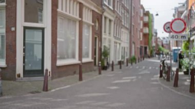 Gündüz vakti bulanık bisiklet ve tuğlalı binaların bulunduğu Amsterdam kentsel caddesinde sakin bir atmosferi olan Hollandalı bir şehrin tuhaf cazibesini yakalıyor..