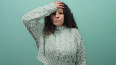 Rahat süveter giyen, gülümseyen ve dokunaklı alnıyla pastel mavisi bir arka plana bakan, sakin ve sakin bir ortamda neşeli ve rahatlatıcı duygular sergileyen bir kadın..