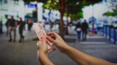 Kentsel caddede Tayvan dolarlarını elinde tutan adam iş, yatırım ve şehir ortamındaki değişimi yansıtıyor, mali kavramları ve işlemleri vurguluyor.