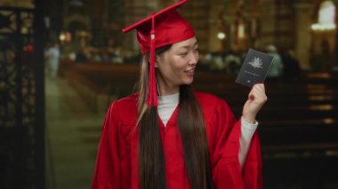 Mezuniyet elbisesi giymiş bir kadın elinde süslü bir şehir dekorunda Avustralya pasaportu ve kültürel çeşitlilik taşıyor..