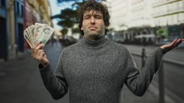 Şehir caddesinde elinde İngiliz sterlinli banknotlar tutan İspanyol bir adam düşünceli bir ifadeyle açık şehir ortamında finansal ya da ekonomik bir temayı vurguluyor..