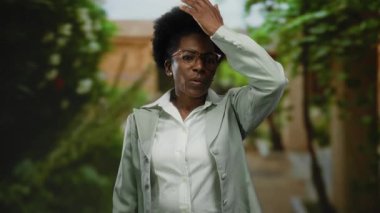 Açık havada gözlük takan kadın, canlı bir şehir sokak ortamında el ele tutuşmuş, beklenmedik bir duygu ve merak anını yakalıyor..