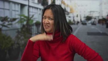 Kırmızı kazaklı genç bir kadın, arka planda saksı bitkileri, doğal ifadeler ve otantik şehir atmosferini sergiliyor..