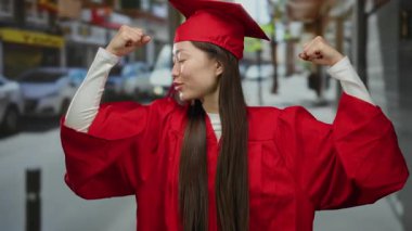 Kırmızı mezuniyet elbisesi giymiş bir kadın, şehir sokaklarında başarı ve başarı sergileyerek akademik bir ortamda kutlama yapıyor..