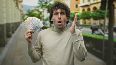 Bir şehir caddesinde sürpriz bir ifadeyle elinde Polonya parası tutan İspanyol bir adam, açık hava ortamında merak ve heyecan karışımı bir şey sergiliyor..
