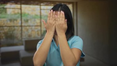 Kadın sevinçle gülümsüyor, elleri havada, steteskop boynunda, kapalı bir odada, neşeli hareketleriyle mutluluk ve sıcaklığını ifade ediyor..