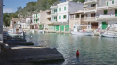 Mallorca 'daki Cala figera limanının bulanık görüntüsü. Açık mavi gökyüzü altında çıkarılmış tekneler, rıhtım, su ve Akdeniz binaları..