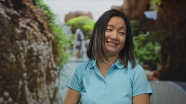 Mavi gömlekli bir kadın, yeşil ve doğal dokularla parıldayan sakin bir parktaki parmaklarıyla kafaya dokunuyor..