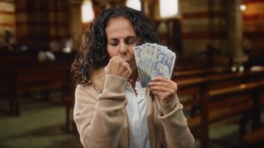 Orta yaşlı bir kadın Romen banknotlarını elinde tutuyor, kilise ortamında yumruğuyla bir jest yapıyor, meydan okuma veya kararlılığını dile getiriyor..