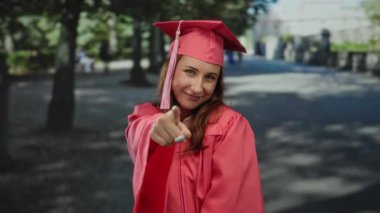 Mezuniyet elbisesi giymiş, güler yüzlü, gündüz vakti akademik başarıyı kutlayan bir kadın..