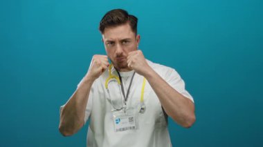 Beyaz önlüklü ve steteskoplu genç bir doktor, izole edilmiş mavi bir arka plana karşı, güç ve güven yansıtan bir savaş duruşu benimsiyor..