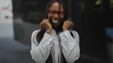 Kırmızı gözlüklü bir kadın aydınlık bir günde şehir ortamında neşe ve mutluluk dolu bir sokakta dikiliyor..