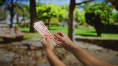 Canlı bir şehir parkında Tayvan banknotları tutan adam, ağaç ve yeşillik zeminli iş ve yatırım temaları sergiliyor..