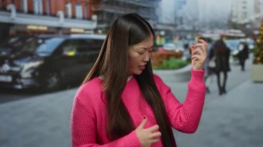 Şehirde canlı pembe süveterle gitar hareketlerini taklit eden, geçmişi bulanık bir kadın.