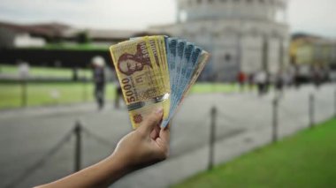 İspanya 'nın Sidikli şehrinde el ele tutuşan Macar paraları. Arka planda kule var. Seyahat ve para konsepti..