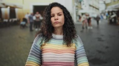 Sokakta renkli süveterli bir kadın karşıt görüşleri tasvir eden bulanık şehir arka planında çapraz kollu ve ciddi bir ifadeyle reddediliyor.