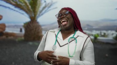 Gün boyunca parkta steteskopla gülümseyen bir kadın canlı şehir manzarası arka planı ve palmiye ağaçlarıyla neşe ve profesyonellik sergiliyor..